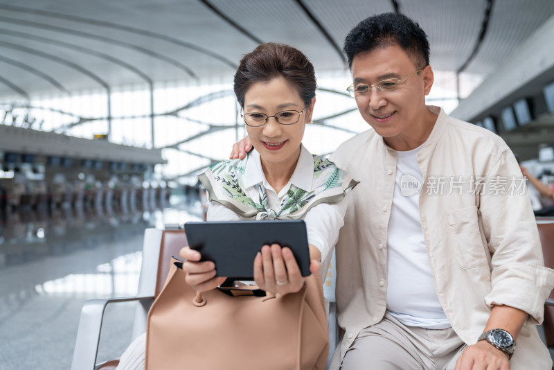 快乐的老年夫妇在机场使用平板电脑