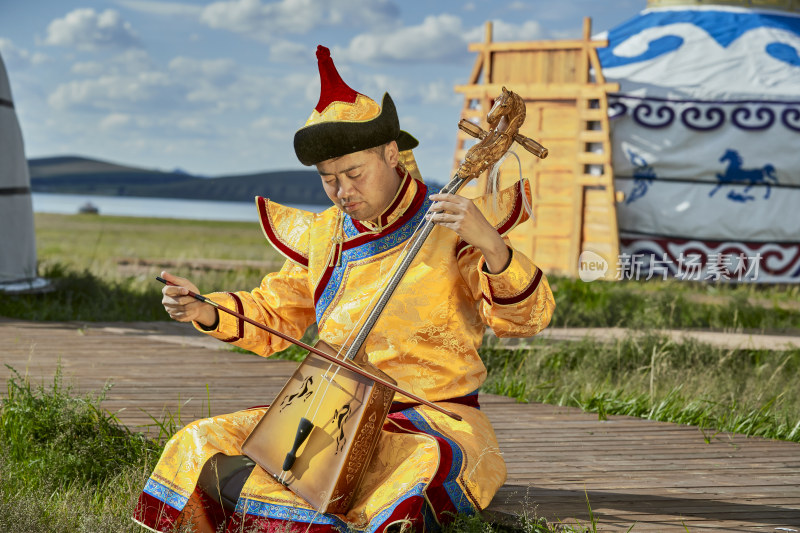 蒙古包前身穿蒙古族服饰拉马头琴的男子