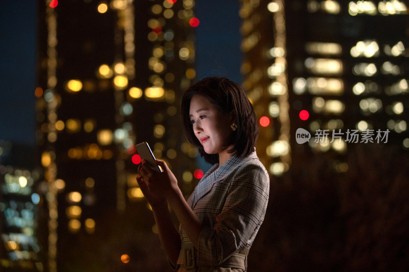 晚上在户外看手机的商务女白领