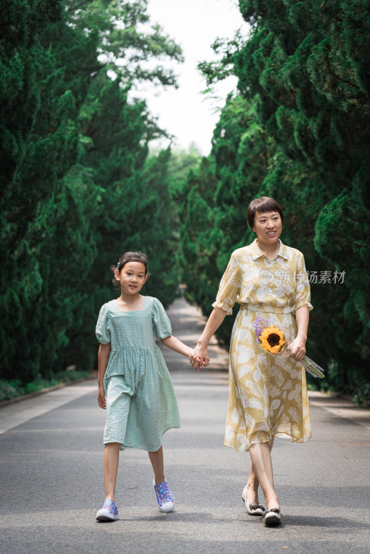 夏天牵手走在林荫道上的中国母女