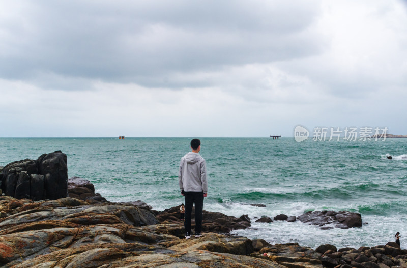 男子独自站在海边礁石上望海