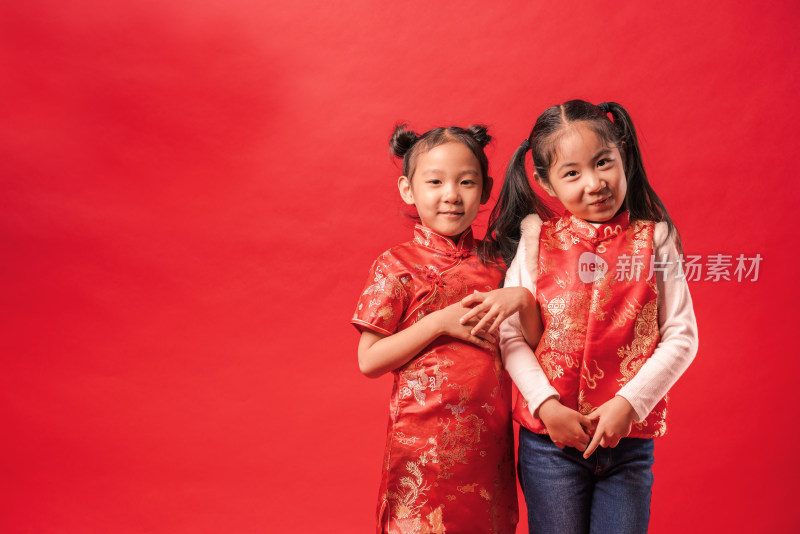 站在红色背景前穿唐装旗袍两个的中国女孩
