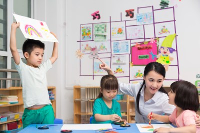 幼儿园女老师和儿童展示绘画作品