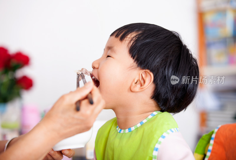 正在给亚洲面孔的小女孩喂饭