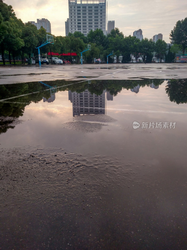 雨后篮球场积水倒影高楼树木的景象