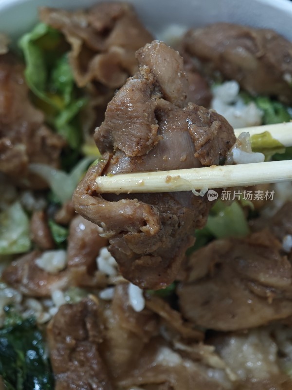 筷子夹起的肉片盖饭