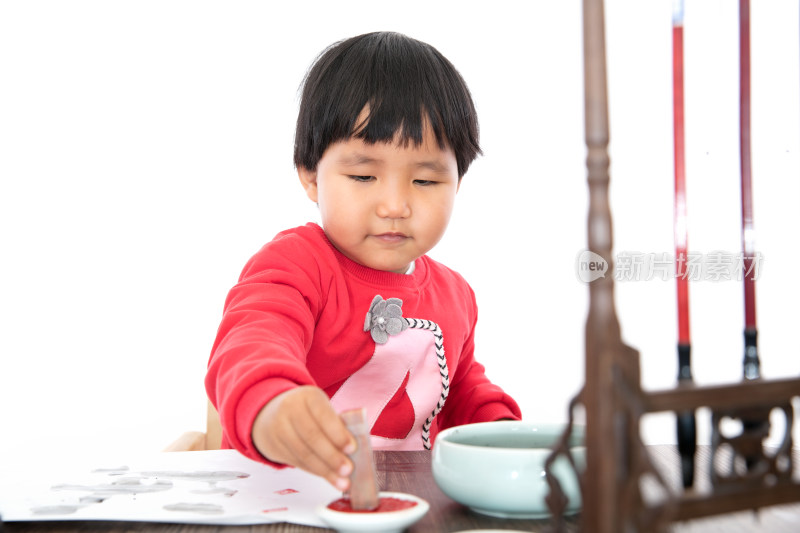 小女孩在书桌前手拿印章放在印泥里