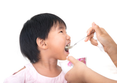 白背景前年轻妈妈正在给孩子喂饭