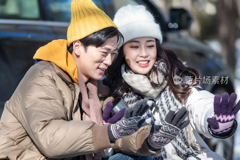 坐在汽车旁的青年夫妇