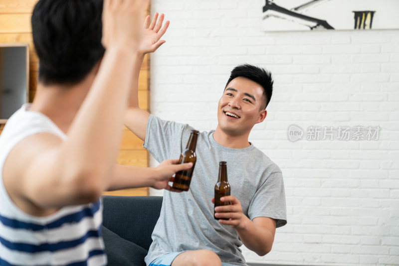 年轻男子坐在沙发喝啤酒