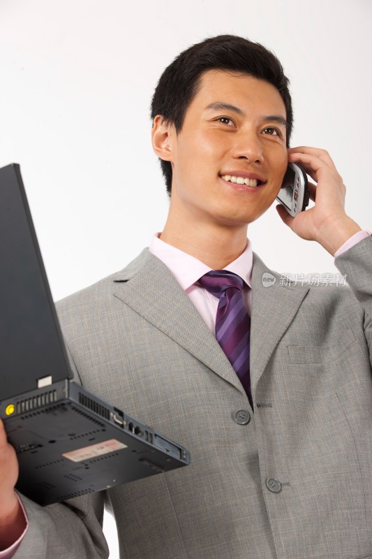 商务男士抱着笔记本电脑打电话