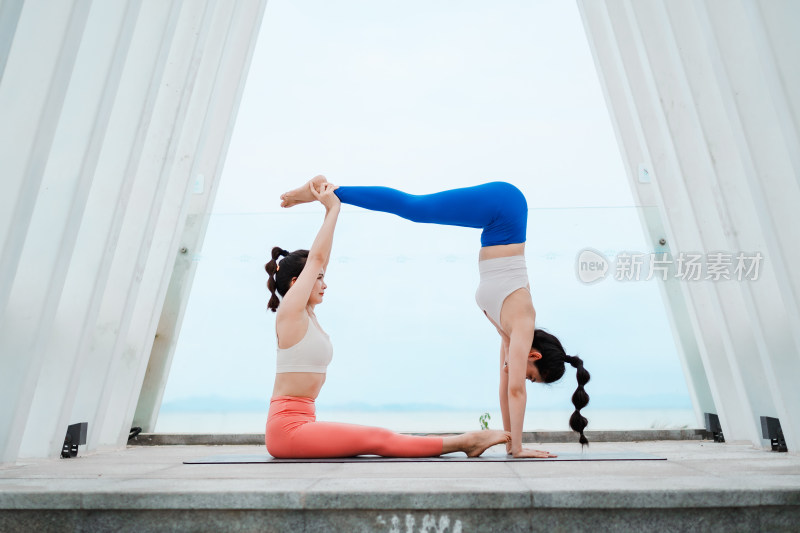 户外宽敞明亮空间里练习双人瑜伽的亚洲女性