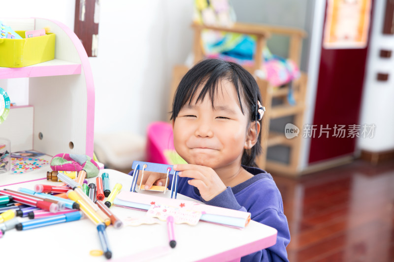 四岁东方小女孩趴在学习桌上玩耍