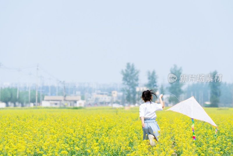 夏天拿着风车在油菜花田中奔跑的女孩