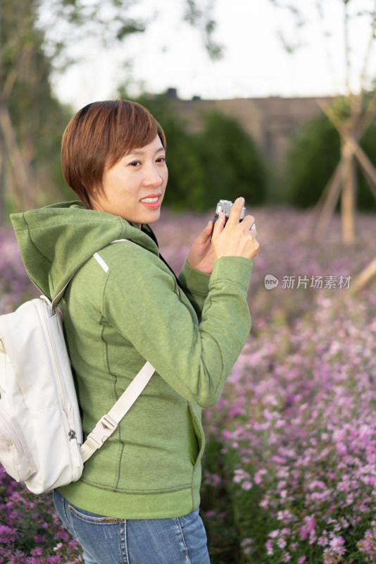 站在花丛中摄影的中国籍女性