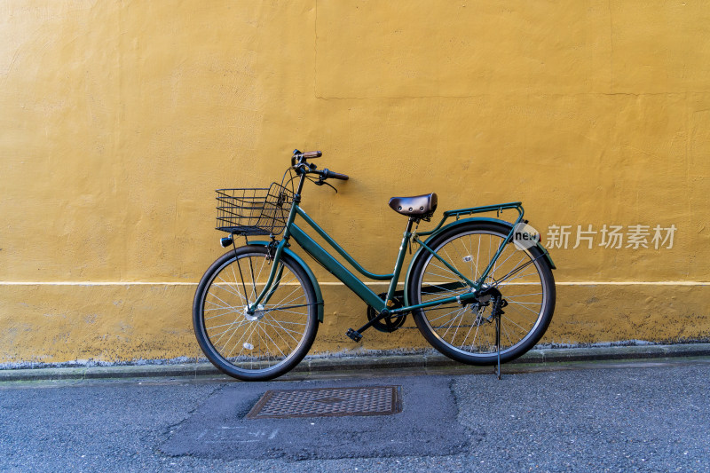 倚靠在黄色墙壁前的复古青色自行车
