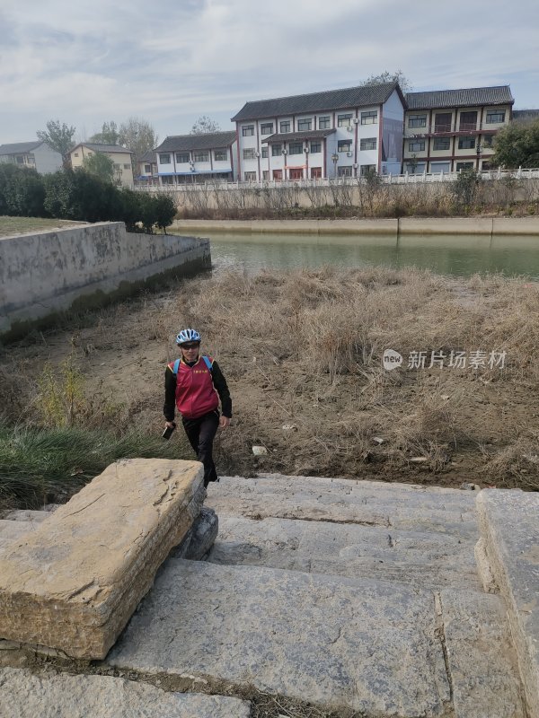 穿骑行服的人走在河边石阶上