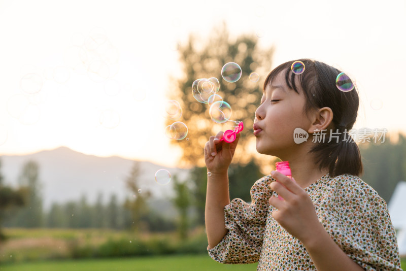 一个小女孩在草地上吹泡泡