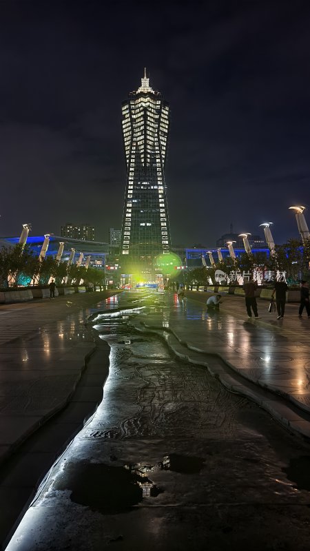 夜晚城市广场中的高塔及行人景象