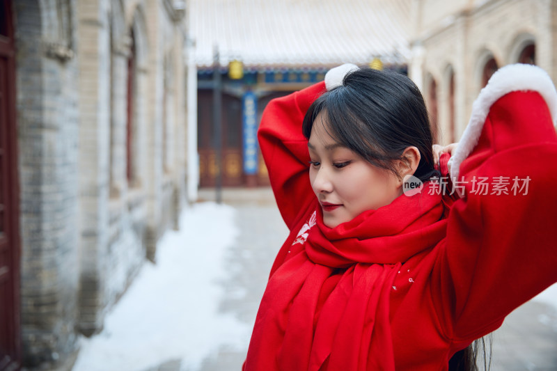 雪后在老城古巷穿着喜庆服饰的亚洲少女