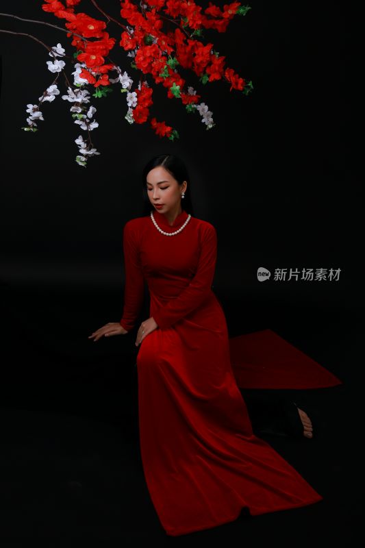 身着红裙女子倚坐花下