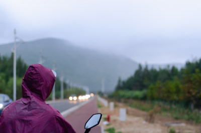 穿着雨衣骑行在雾气弥漫的山村