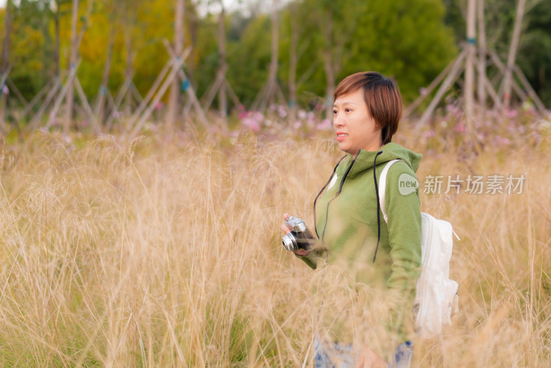 站在干枯草丛中拍照的中国籍女性