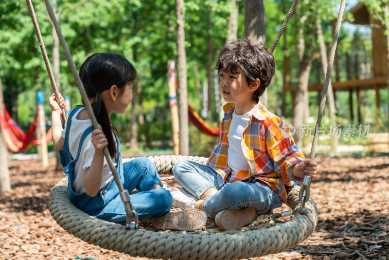 两个小孩子面对面开心荡秋千