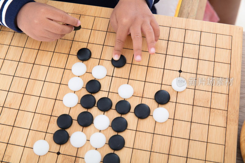 棋盘上小孩子的手在摆放围棋棋子