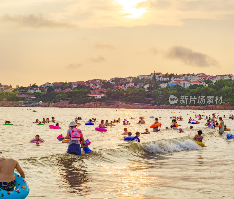 青岛汇泉湾夕阳下，海水浴场中的人们