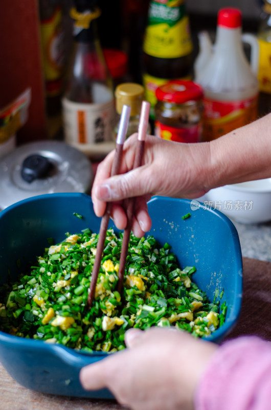 手用筷子搅拌韭菜鸡蛋馅料