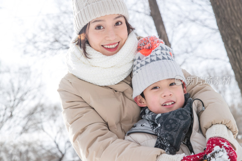 年轻妈妈带着孩子在雪地玩耍