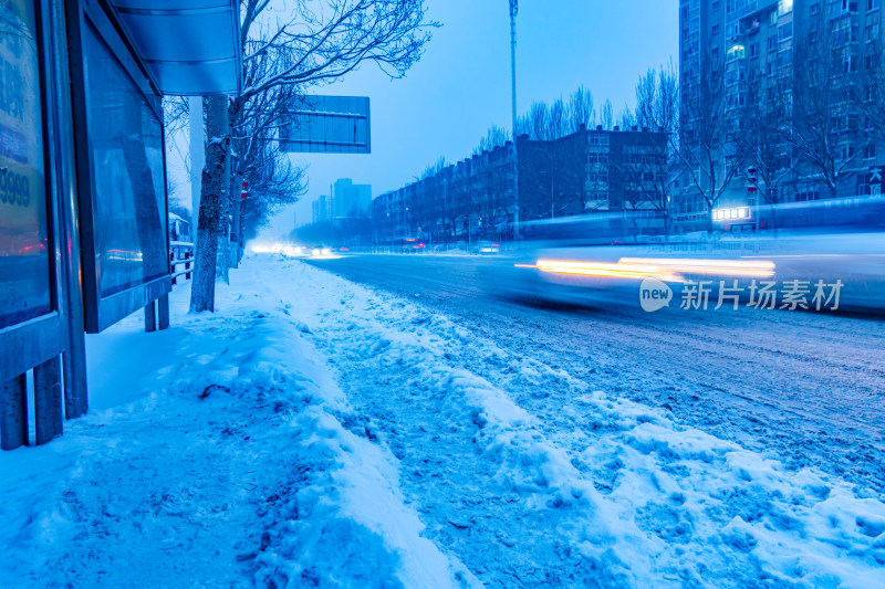 雪天夜晚亮灯的居民楼外景马路街道