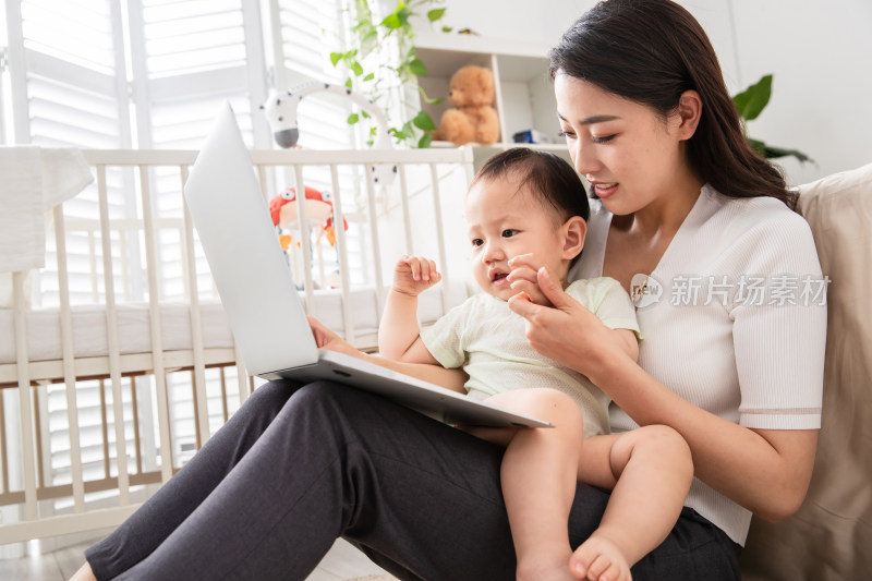 在家使用电脑的年轻妈妈和宝宝