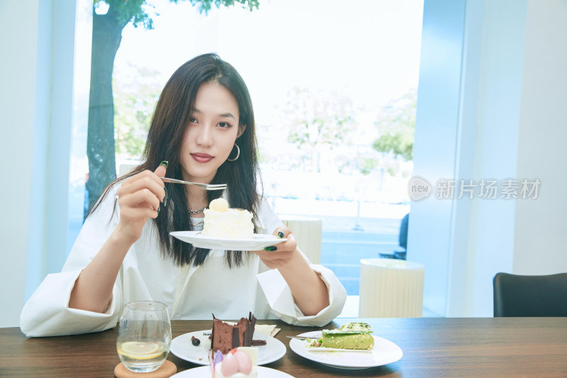 在烘焙店吃蛋糕喝饮料的可爱亚洲少女