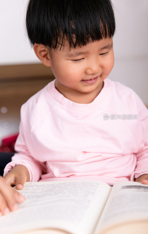 特写把书本摊在腿上看书的小孩子