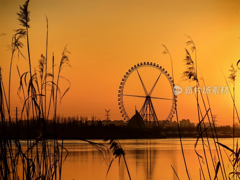 夕阳下的浪漫地标：湖畔摩天轮的金色剪影