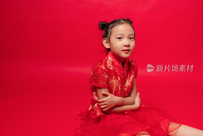 坐在红色背景前穿旗袍的中国女孩
