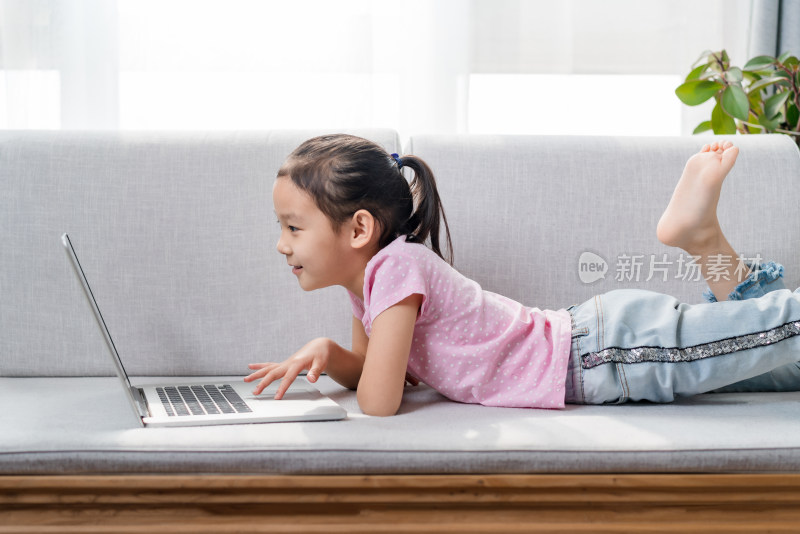 趴在沙发上使用笔记本电脑的女孩