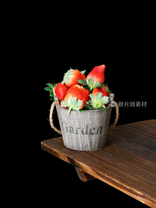 黑色背景上，一篮子的新鲜水果草莓