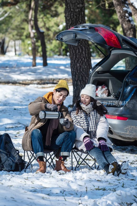 坐在汽车旁的青年夫妇