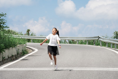 晴朗的夏天午后走在盘山公路上的东方女孩