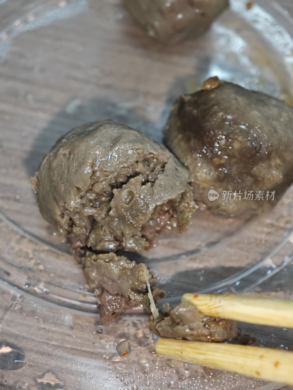 筷子夹起塑料盒中的肉丸