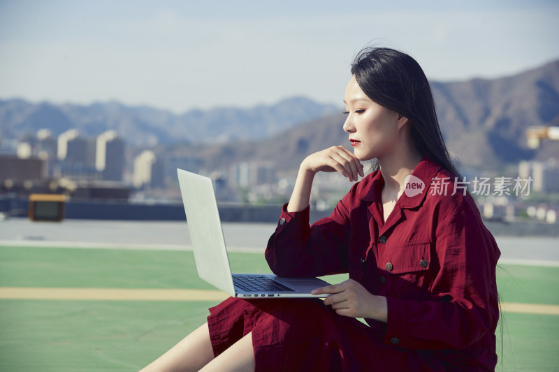 亚洲商务年轻女性在楼顶停机坪使用电脑办公