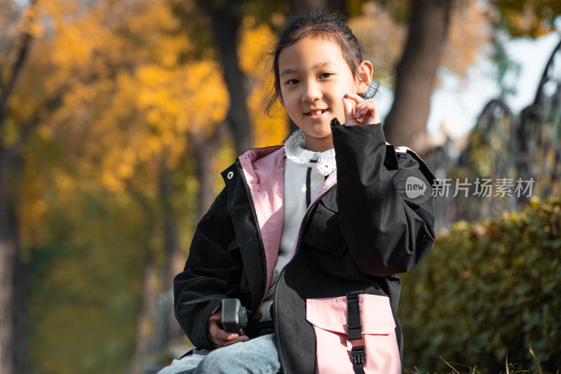 秋天坐在树下玩耍的中国女孩