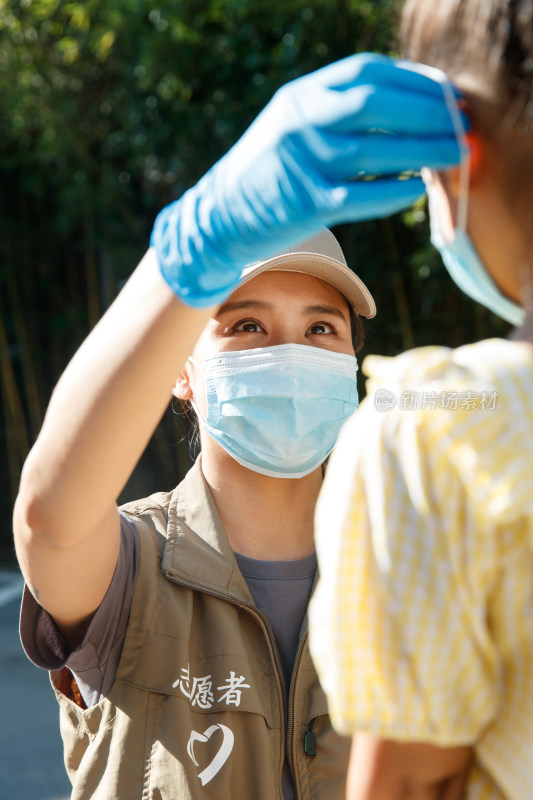 社区志愿者帮小女孩戴口罩