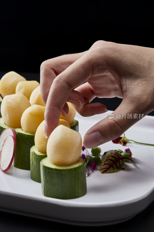 黑色背景上的创意美食手打马铃薯球配乳瓜段
