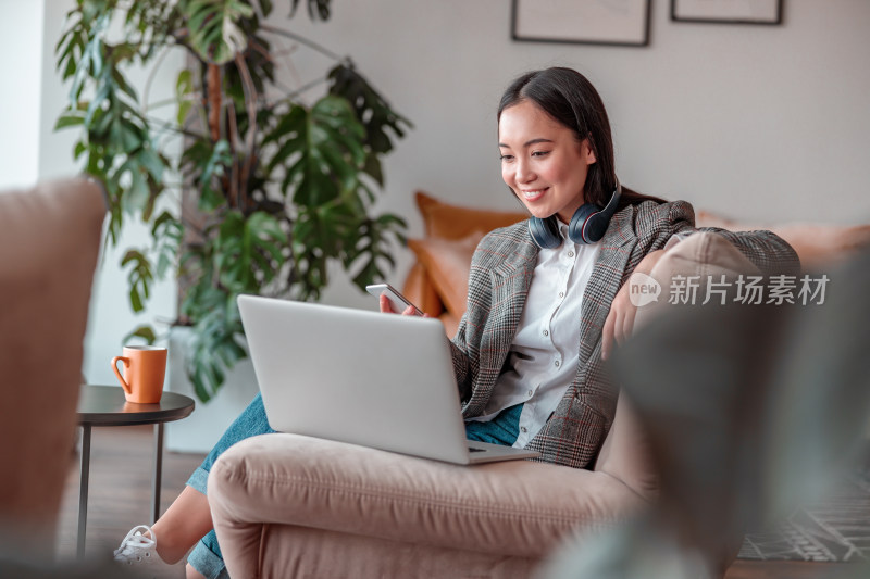 女子沙发上使用电脑和手机