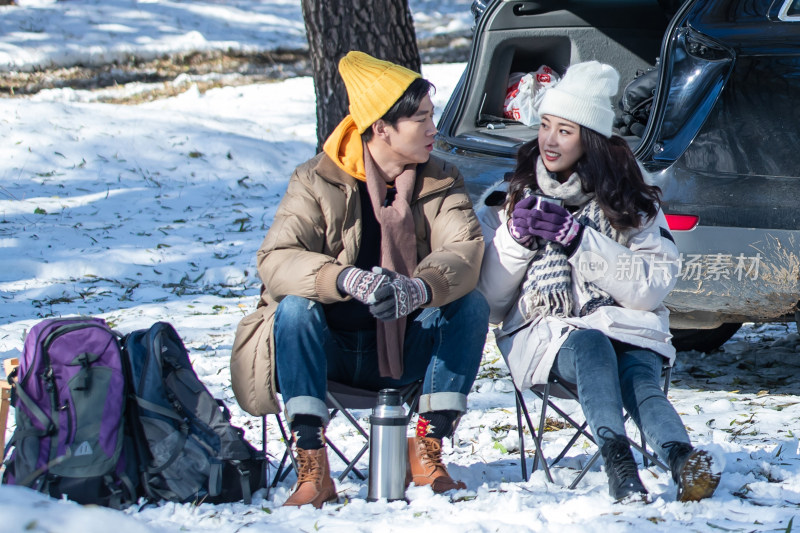 坐在汽车旁的青年夫妇