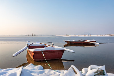 冬日湖面停泊着覆雪的小船
